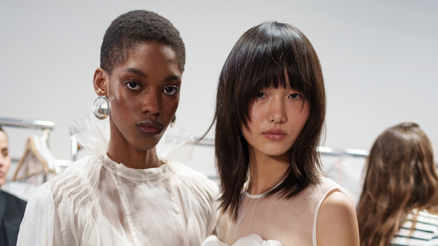 one black model and one asian model wearing white outfits with glowing skin side by side