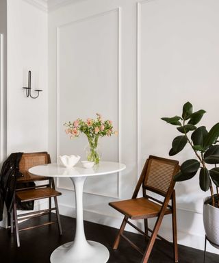 A contemporary white table and two wooden chairs in a studio apartment corner