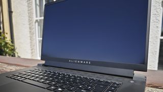 A dark grey Alienware m17 R5 gaming laptop sitting on a wooden table