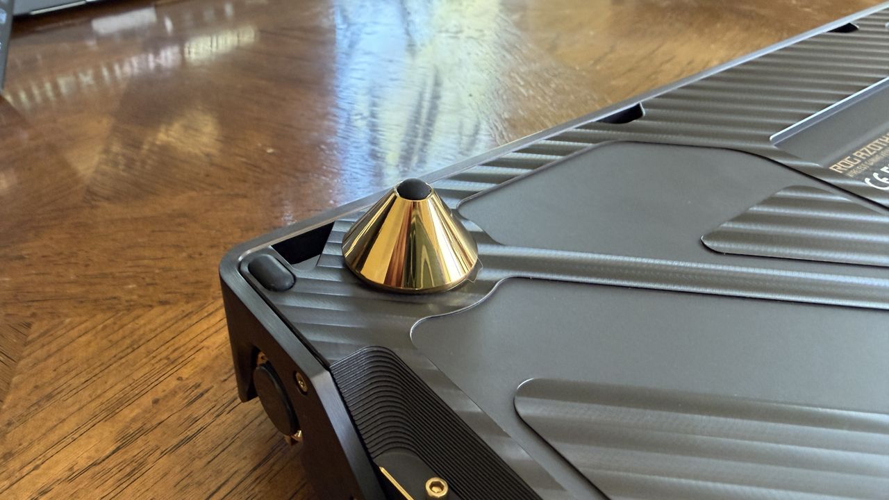 Close-up of a gold cone footrest on a matte black ASUS ROG Azoth Extreme Edition 20 keyboard with a textured surface.