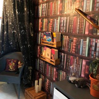 bedroom with book shelves chair and black curtains