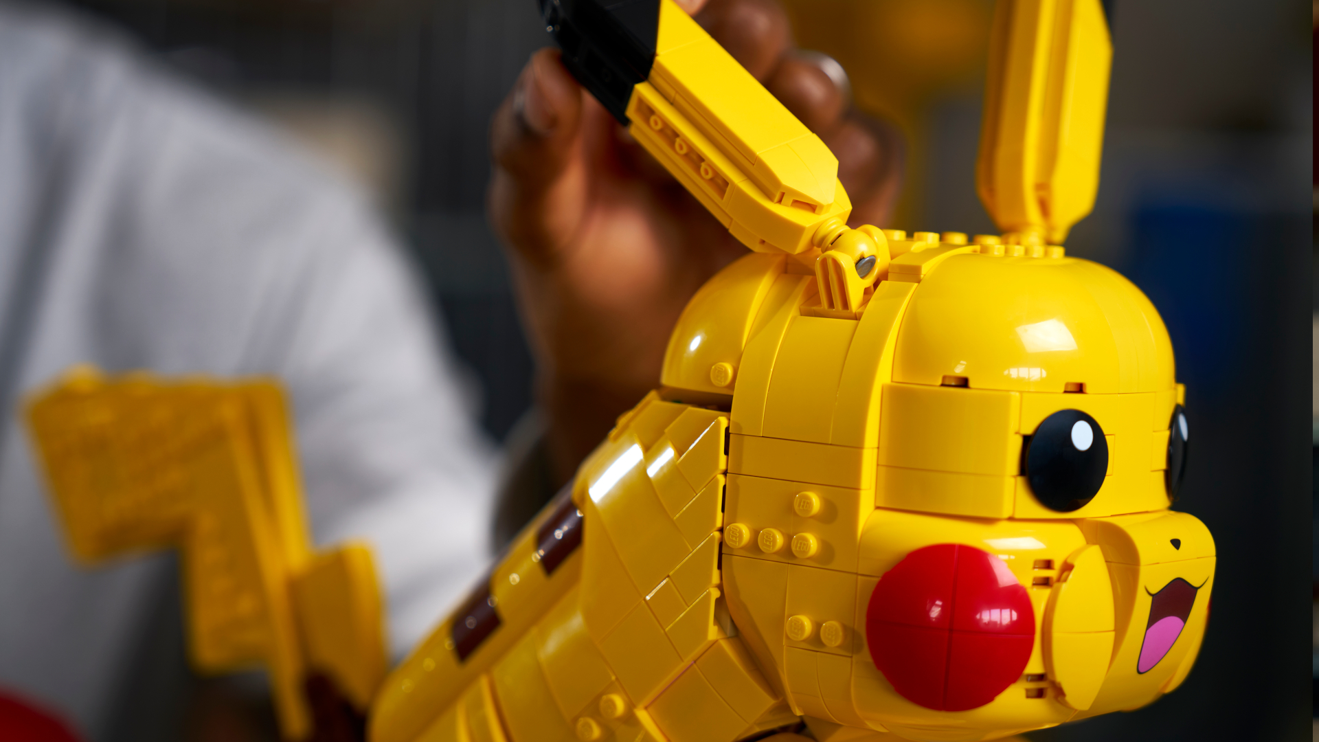 Lego Pikachu and Poke Ball set, seen from the side, with a hand moving the ear