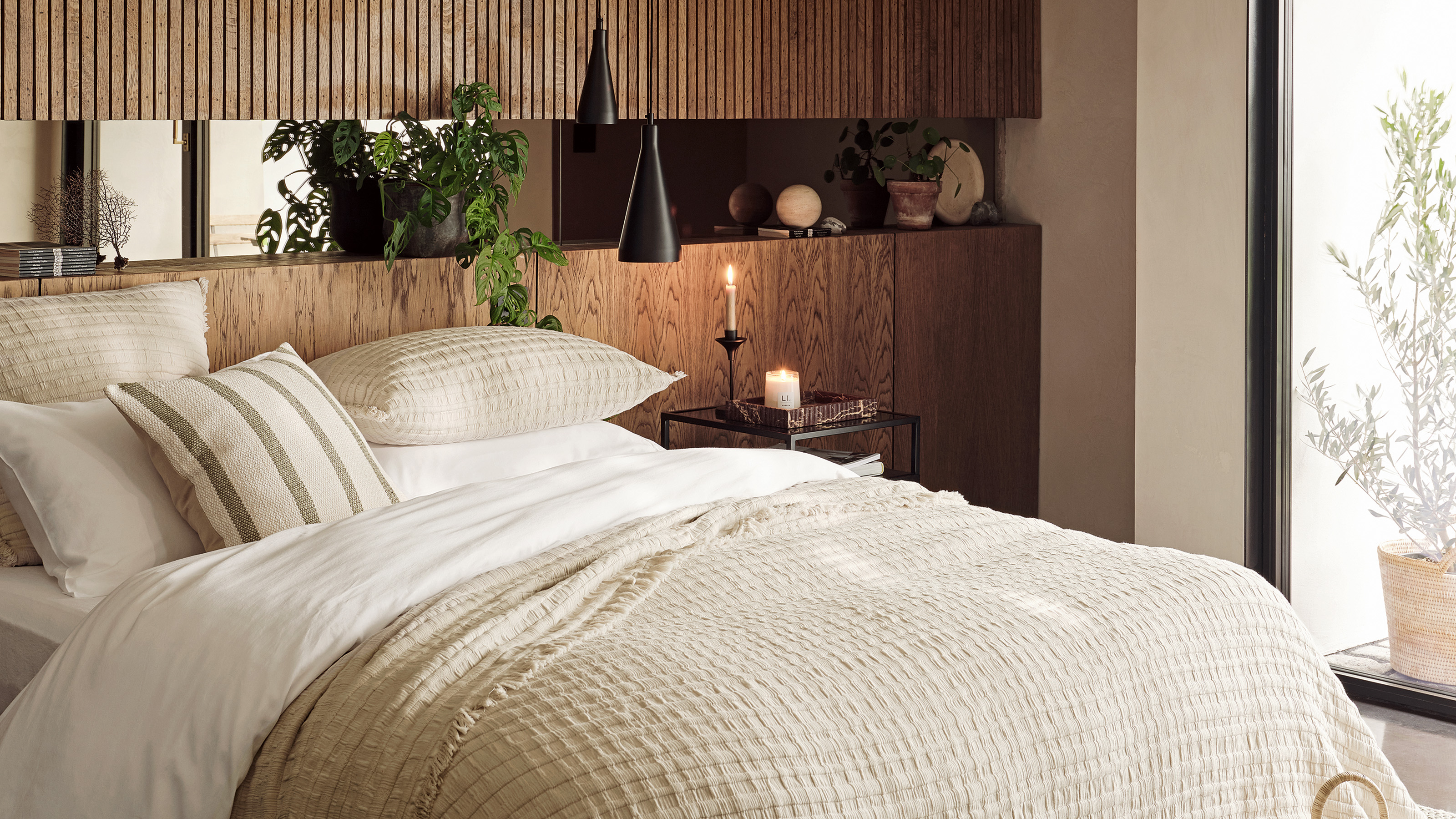 bedroom fluted panelling at the top of the wall and solid wood planks on the lower half the bed is dressed in cream waffle cotton blanket and white cotton duvet cover