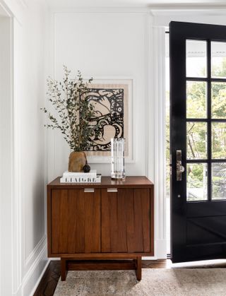 An entryway with a small wooden side table and a piece of artwork hung on the wall