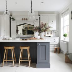 an open plan neutral shaker-style kitchen with a dark coloured kitchen island with a breakfast bar