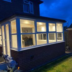 Conservatory exterior at night, with lights on inside