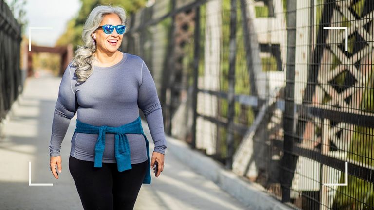 Woman smiling with sun glasses on walking for weight loss over a bridge