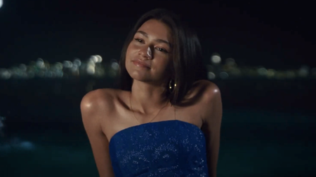 Zendaya smiling while sitting on the beach at night in electric blue dress in Challengers