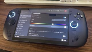 A Lenovo Legion Go S SteamOS sitting on a desk showing the settings page with joystick RGB customization options
