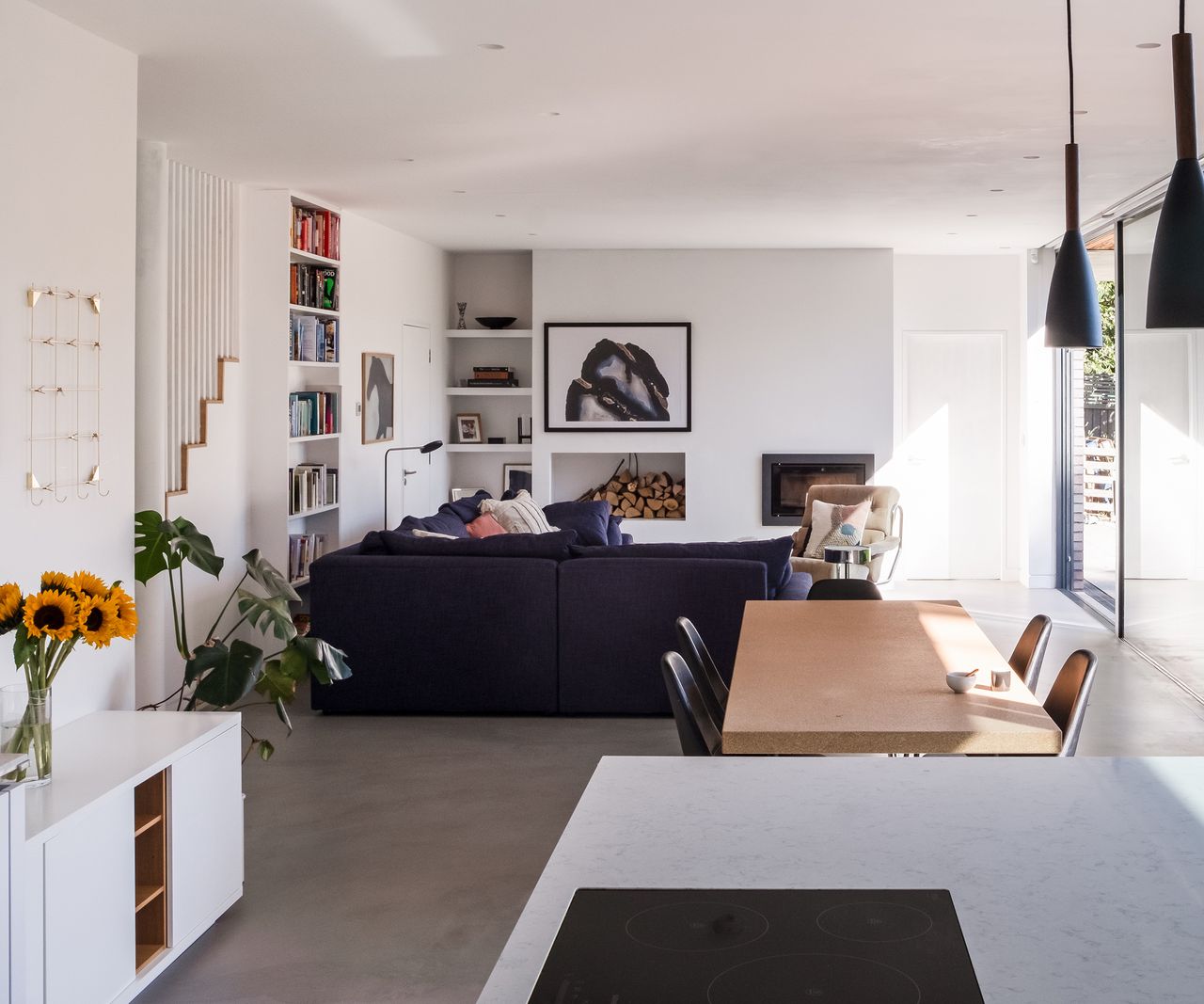 A long open plan living room, dining and kitchen area with sliding glass doors all along one side