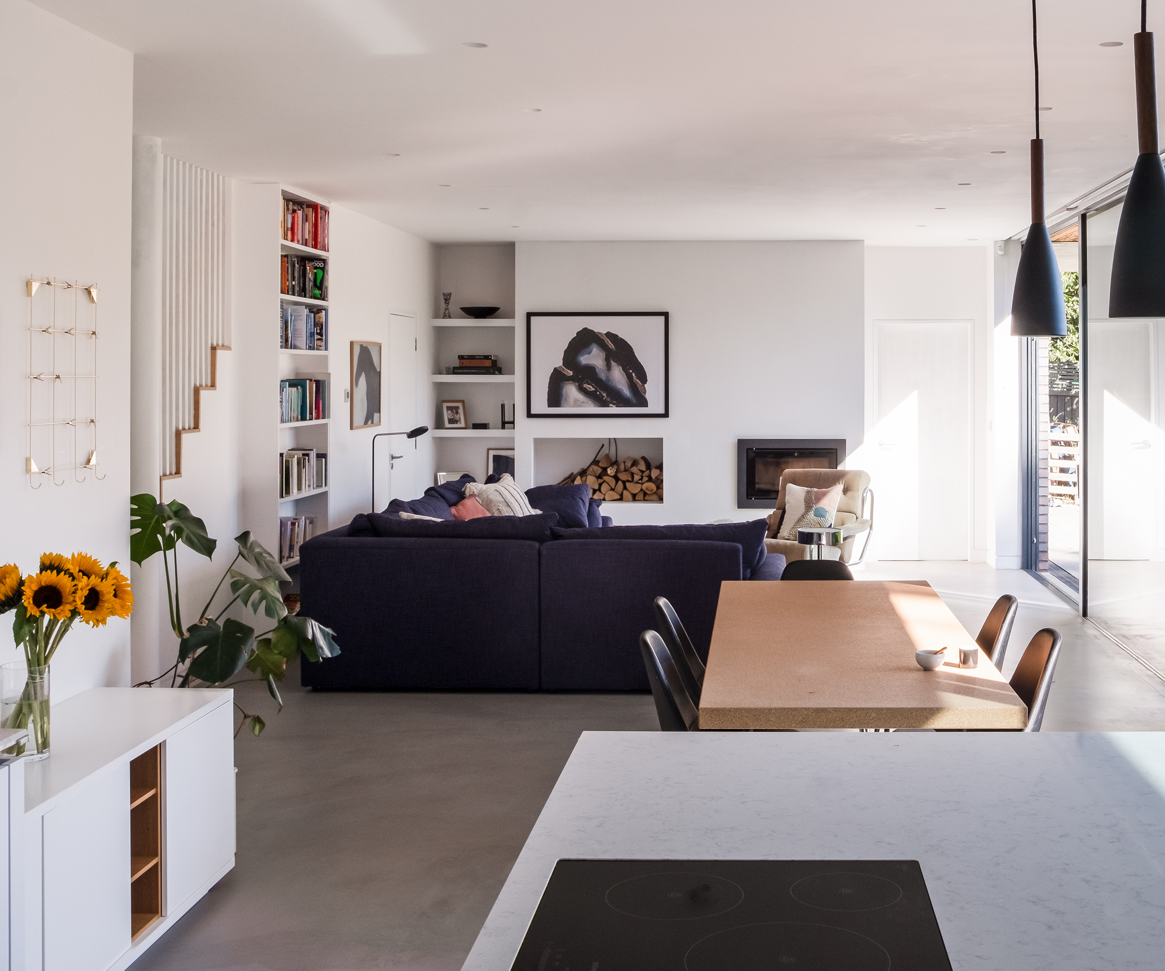 A long open plan living room, dining and kitchen area with sliding glass doors all along one side
