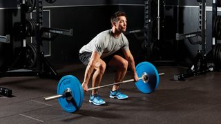 Man holding a barbell resting on the floor, with a wide grip