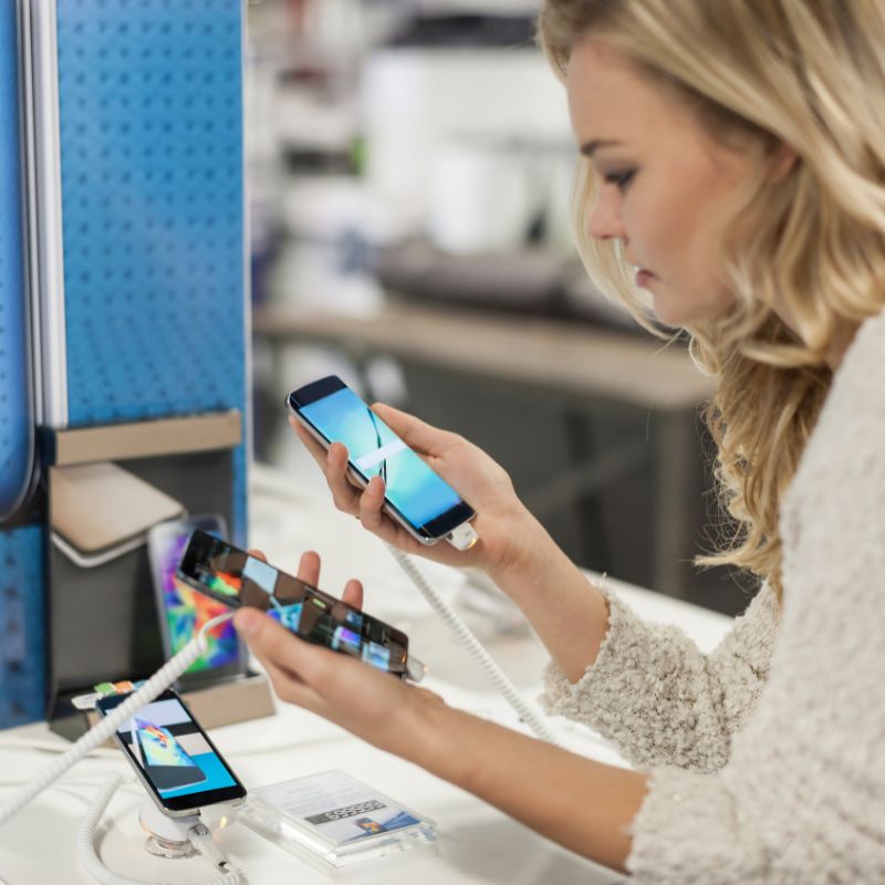 A woman comparing two phones in a store.