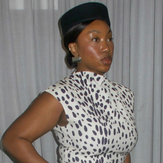 Woman wearing black and white dalmatian print dress and black pillbox hat.