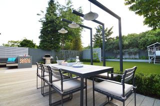 family garden ideas: table with overhanging lighting in garden designed by Harrington Porter