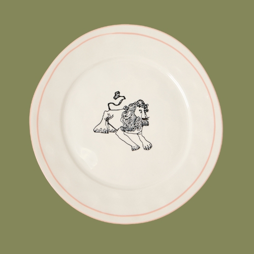 A white ceramic plate with a black lion illustration on it in front of a green background.