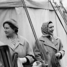 Princess Margaret wearing a headscarf standing next to the Queen Mother, looking away