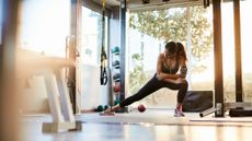 Fit young woman stretching in a home gym, surrounded by home gym equipment