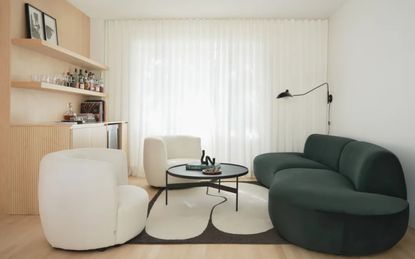 living room with white walls, green sofa and white accent chairs