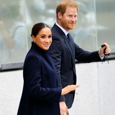 Meghan Markle smiles and waves as she walks with Prince Harry