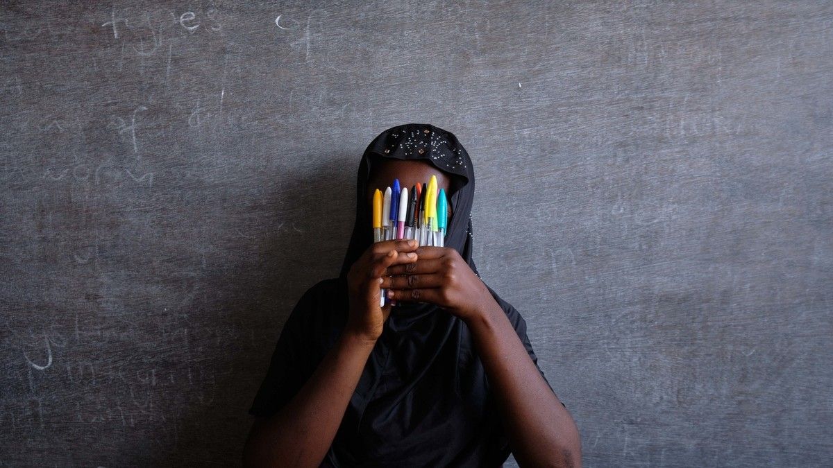 Girl holding pens in front of her face