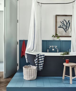 teal painted bathroom with teal panelling, bath and stool