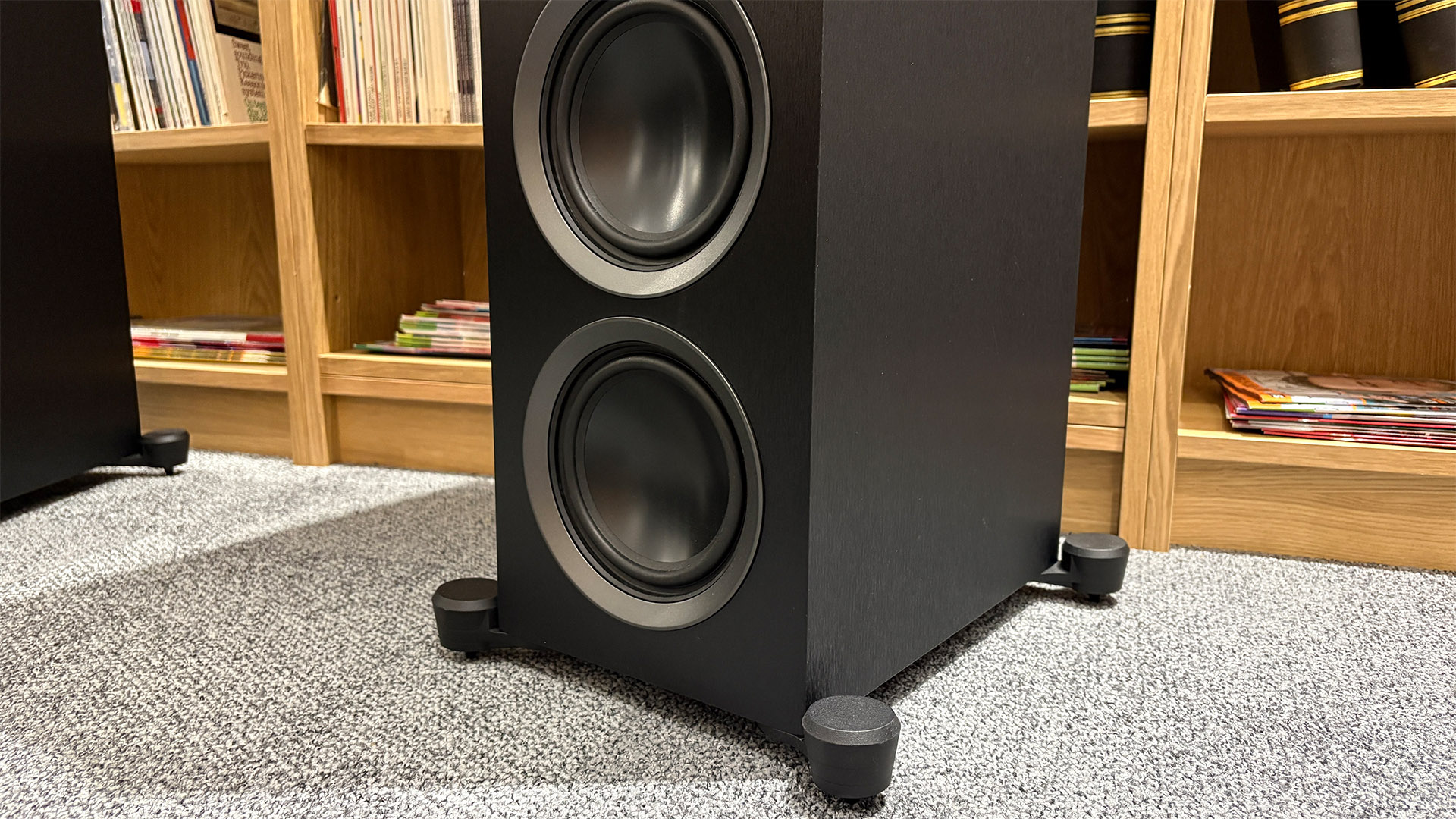 Martin Logan Motion Foundation F1 floorstanding speaker on grey carpet in front of bookcase detail of bottom of speaker