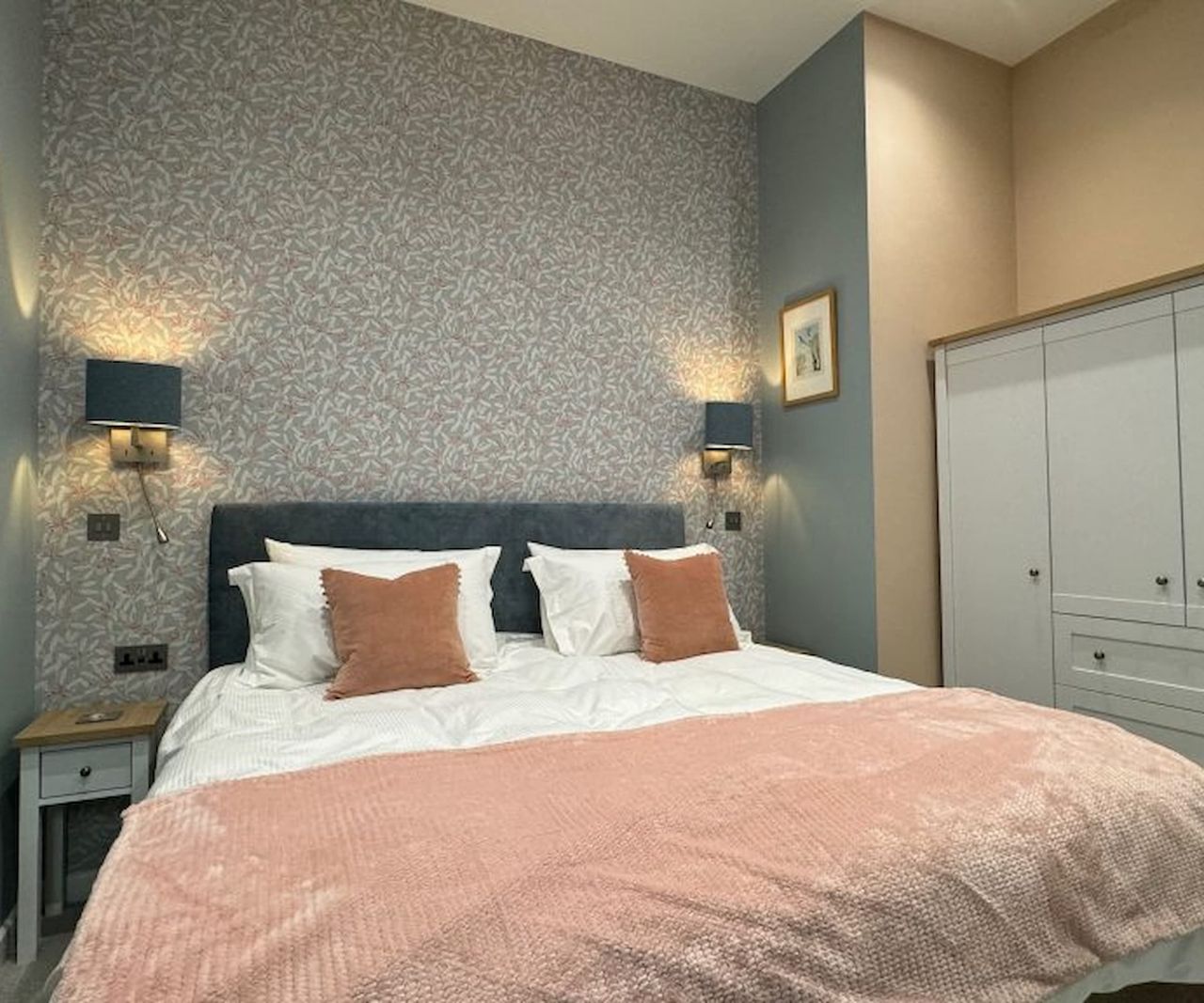 A master bedroom with a blue cupboard and pink sheet covers