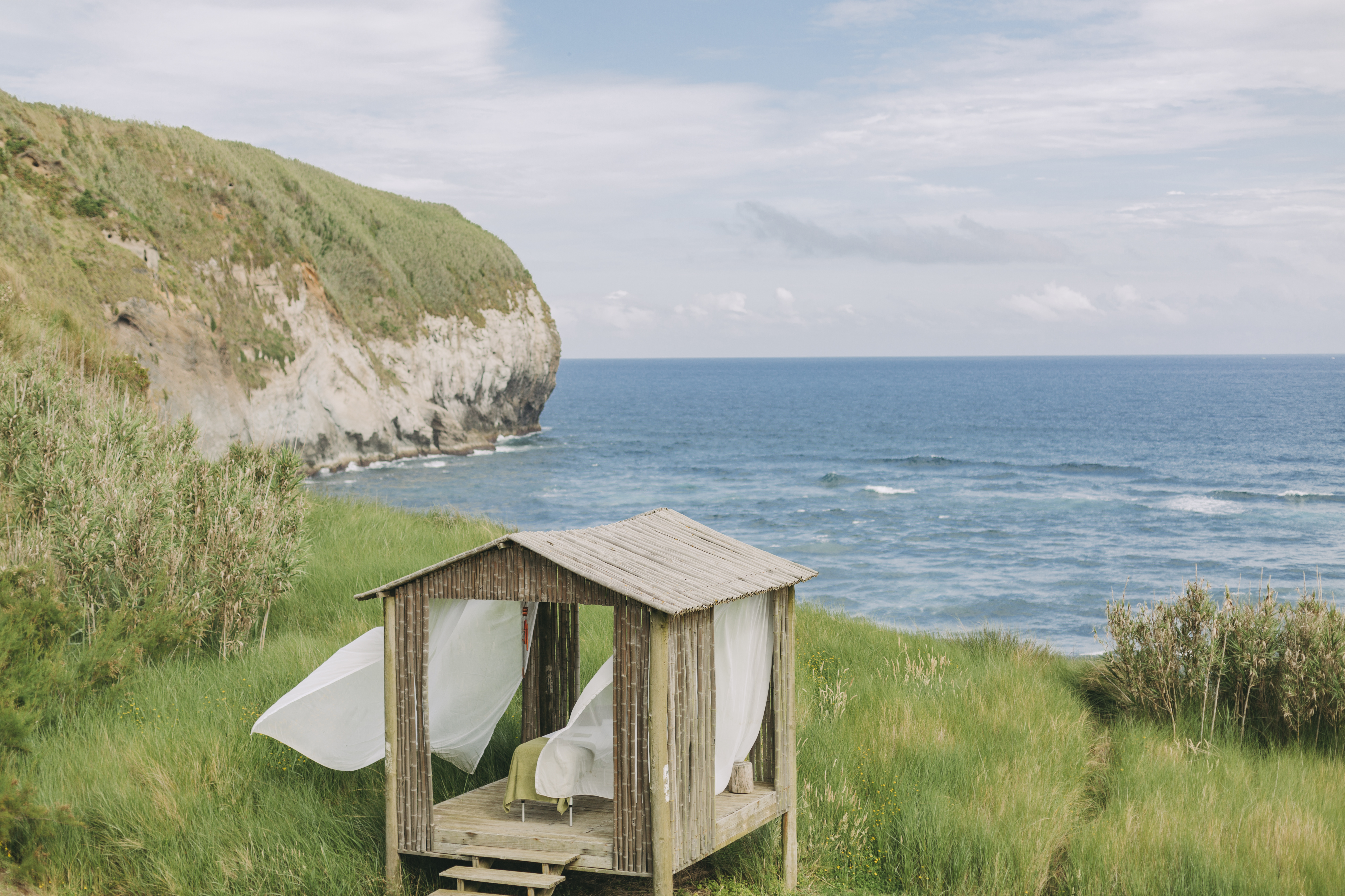 An eco-resort punctuated by wooden finishes, thriving plants, and mid-century modern furniture, as well as breathtaking coastal views.