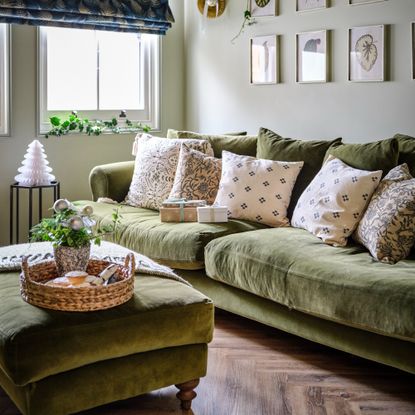 A living room with a green velvet 3-seater sofa with a matching ottoman decorated for Christmas