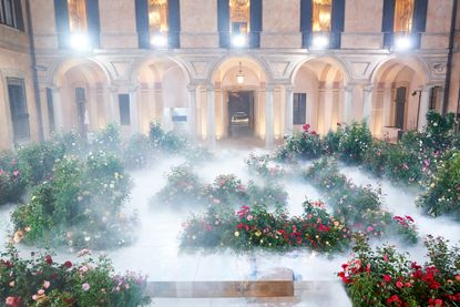 A maze of flowers and mist in front of a building with arches