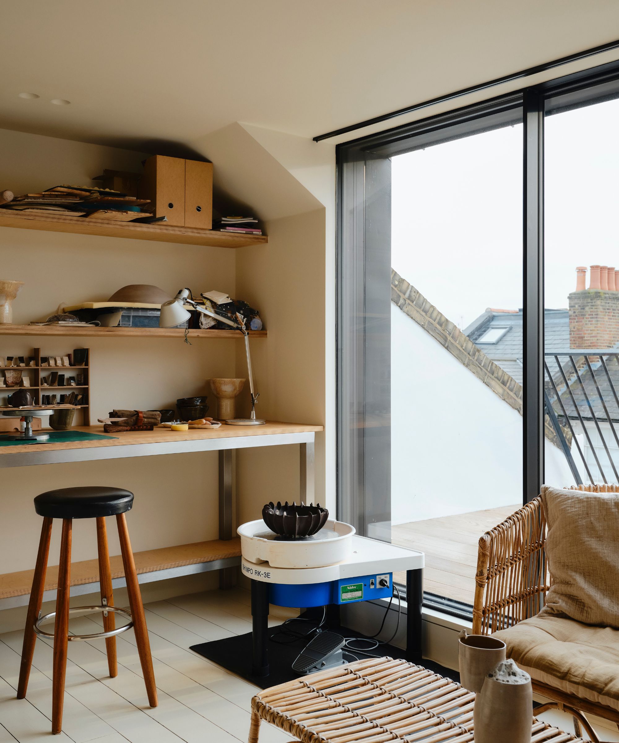 Potter's home studio with sliding doors onto a balcony and wooden shelves