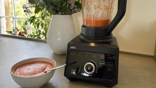 A bowl of carrot soup next to the Braun Powerblend 9 Jug Blender