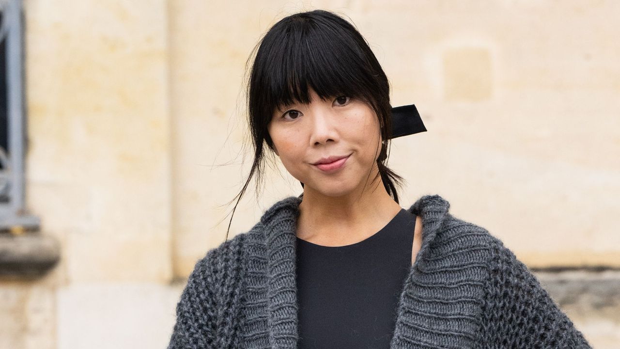 Susie Lau wearing a black top, a grey knit cardigan with her hair tied up, showing off her blunt fringe - best products to style a fringe