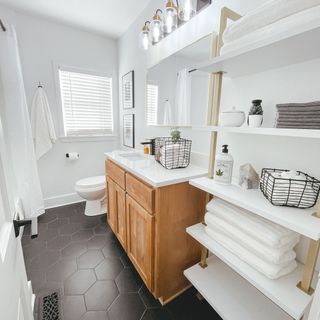 Black tile bathroom with white cabinetry, towels and wooden cabinet