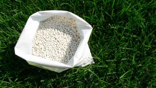 A bag of open granular fertilizer on the lawn