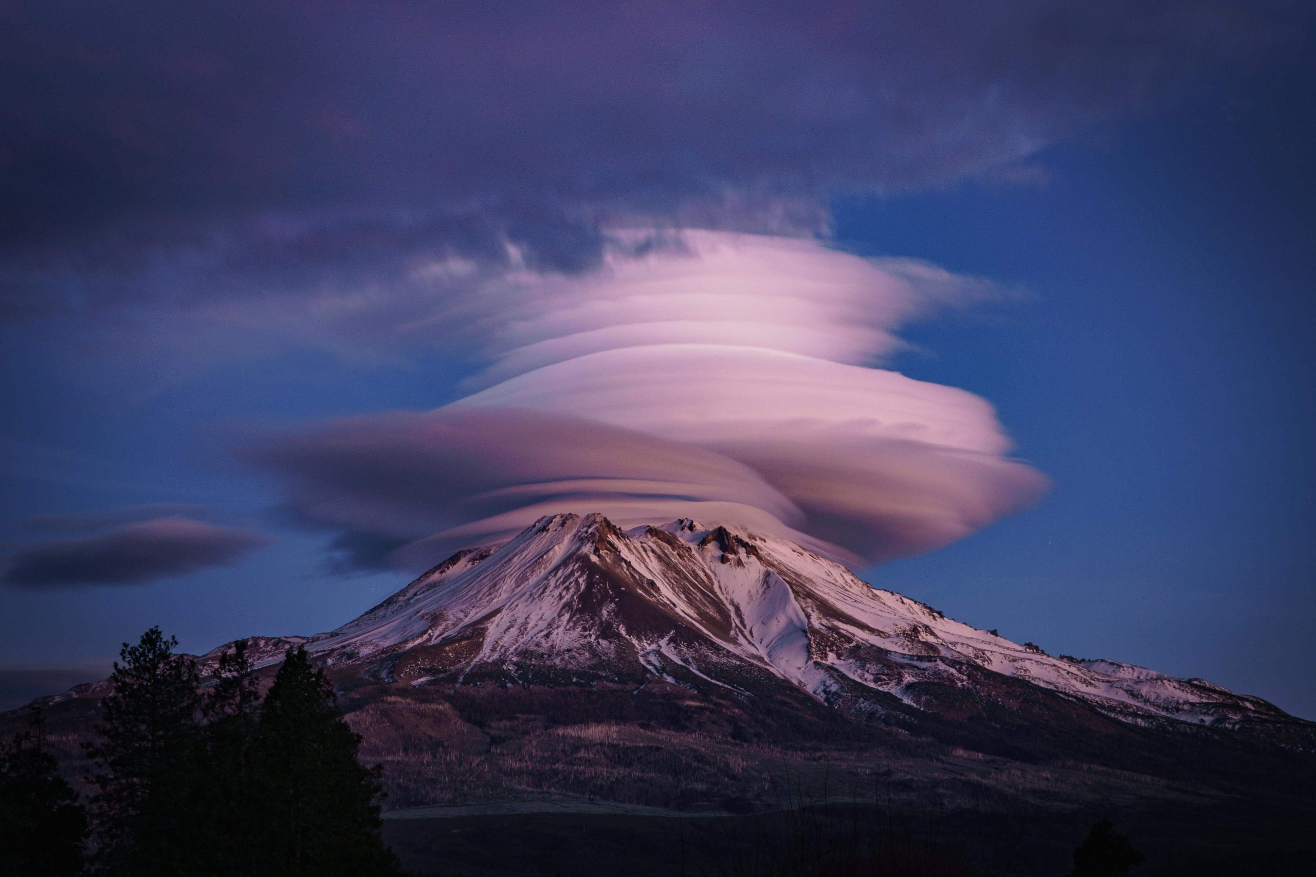 Wispy clouds in disk formation above volcano.