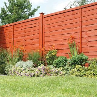 Brown garden fence behind plant bed