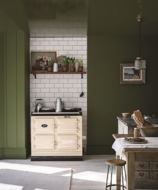 A dark green kitchen with a matching ceiling, broken up by a white subway tiled wall section