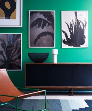 Green room, leather chair, artwork on walls, black and wood sideboard