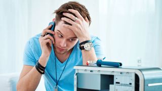 Young man has problem with his computer, trying to reach hotline.