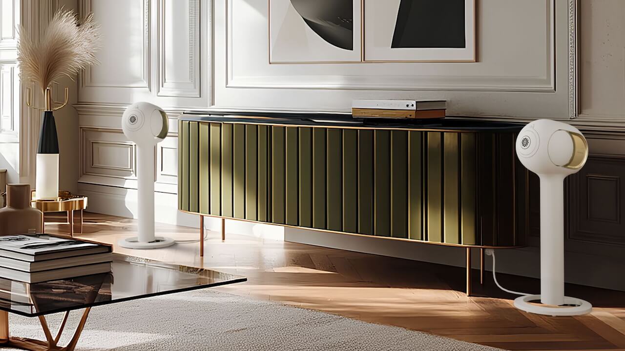 Devialet Phantom Ultimate speakers in white on either side of a green-fronted wooden sideboard in a room with nice sunlight coming in
