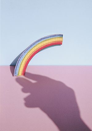 A photograph of a rainbow and the shadow of a hand, shot on a background of pink and blue tiles by Marazzi