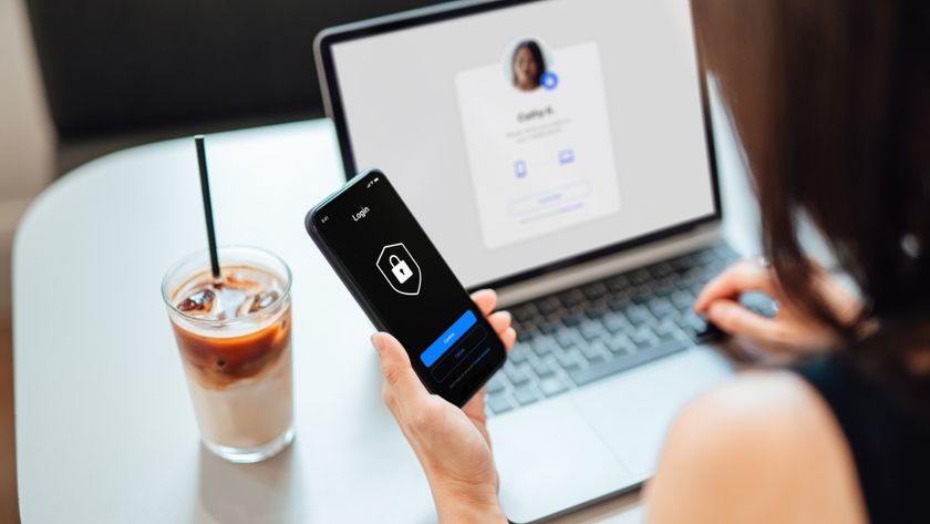 person using phone with locked screen with iced coffee and laptop in background