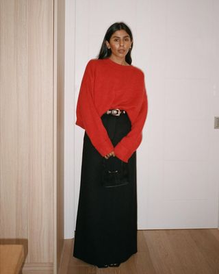 @monikh wearing a red jumper and long black skirt