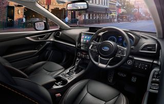 Daytime image of a XV E-Boxer Subaru plug-in hybrid interior, black leather seats, centre console, dash board and steering wheel, road, passers bu=y on the street opposite, brick buildings