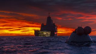 A sunset shot of the USS John P. Murtha during recovery test procedures for NASA's Orion crew capsule, seen to the right.