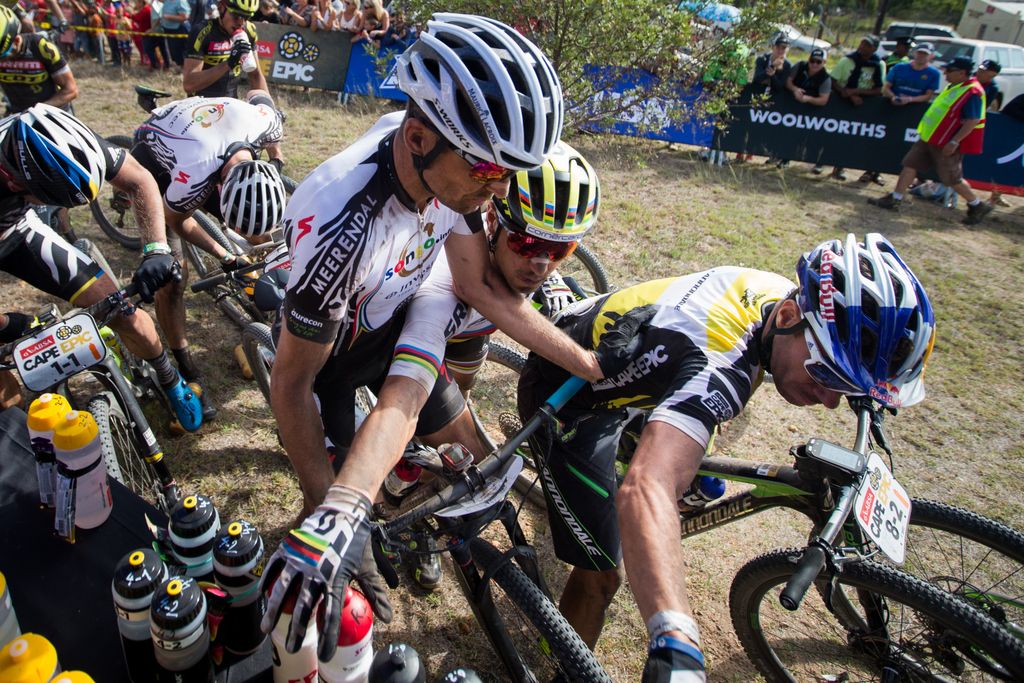 Nino Schurter tries to squeeze in and grab a bidon