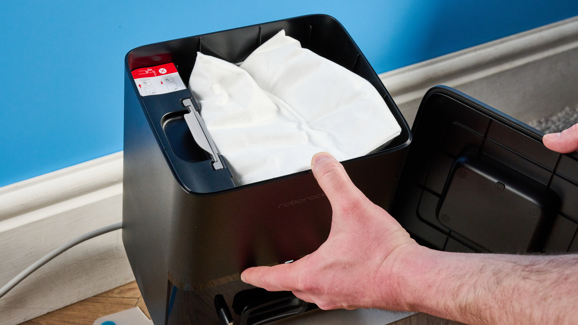 Roborock Q10 S5+ photographed on a wooden floor in front of a blue background