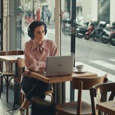A person using a HP laptop in a cafe next to a window